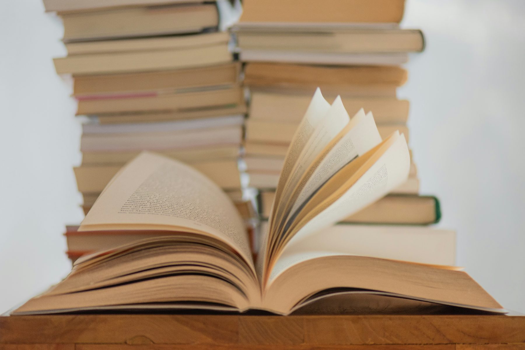 An open book in front of a tall stack of books