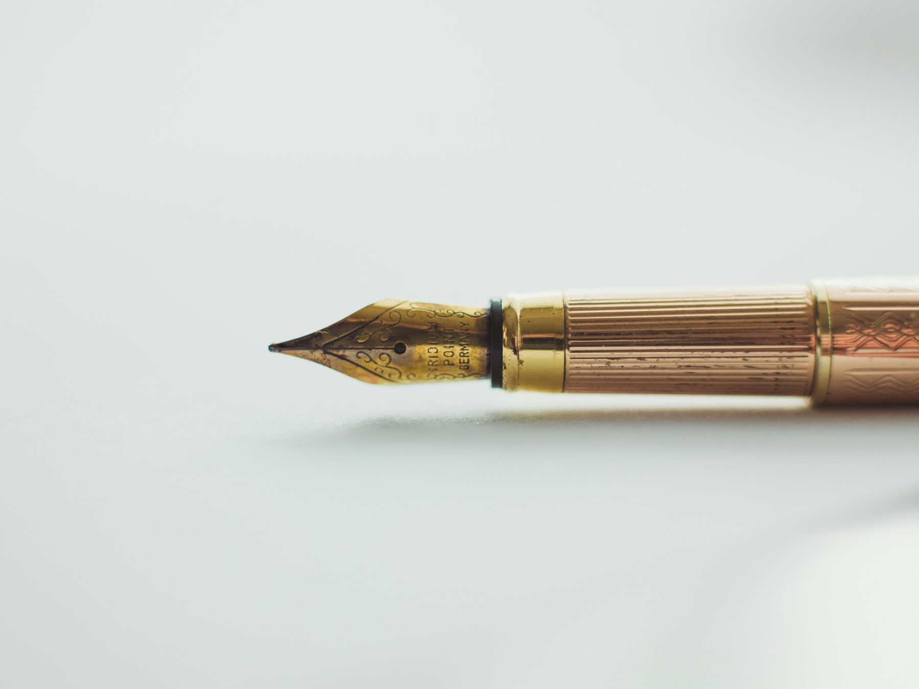 A gold fountain pen resting on white paper