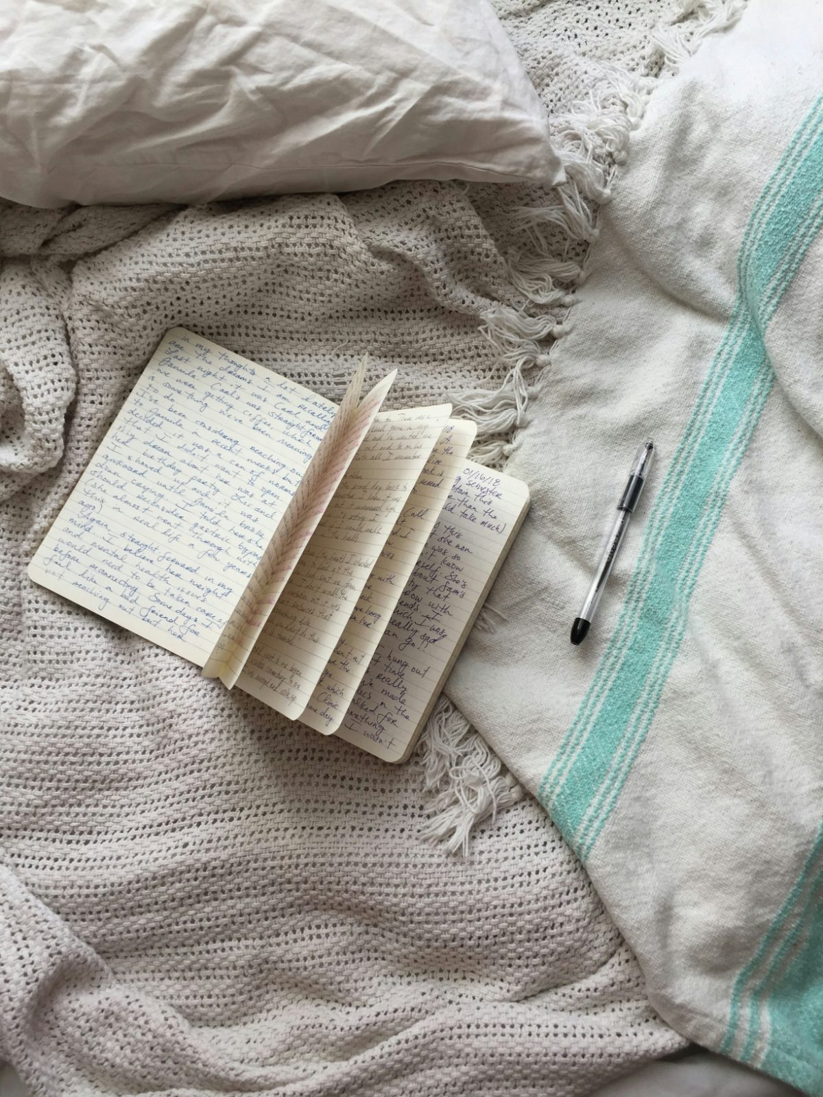 A handwritten journal and pen on a soft throw blanket